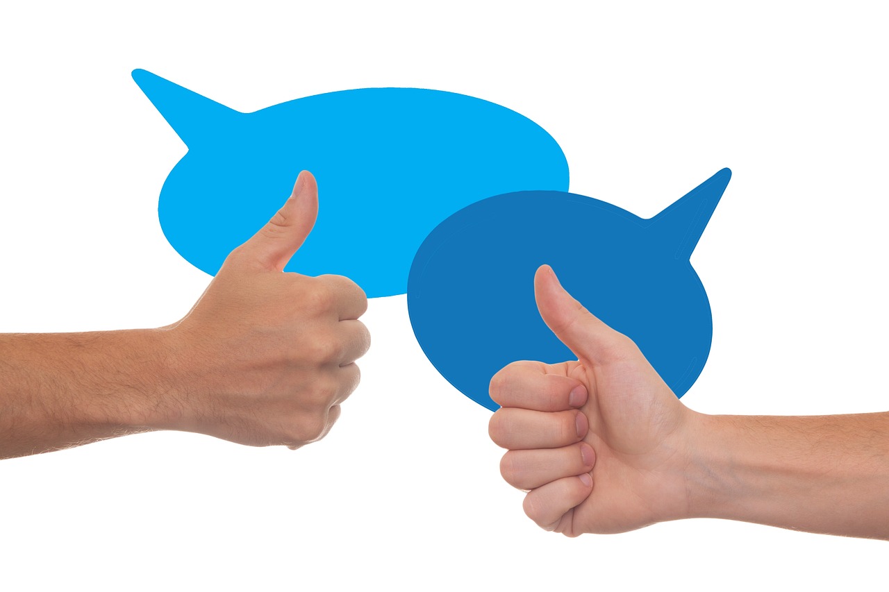 zwei Hände mit dem Handzeichen "Daumen hoch" vor zwei blauen Sprechblasen