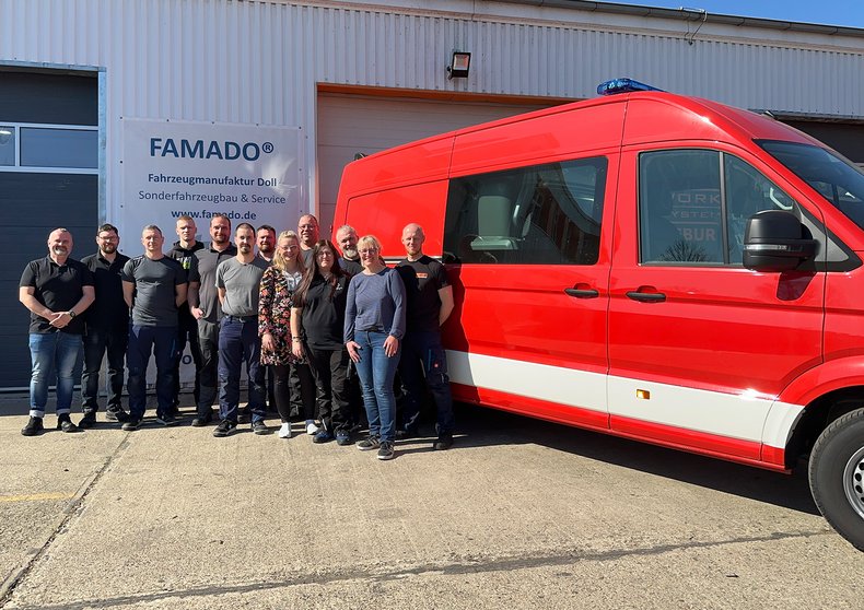 Das Team der Rettungstechnik Doll GmbH vor einem Kundenfahrzeug
