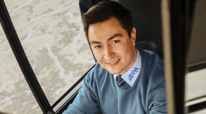 Ein Mann sitzt am Steuer eines Busses und fotografiert sich im Rückspiegel