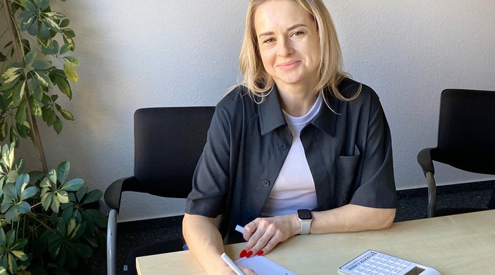 Eine Frau sitzt an einem Schreibtisch und hält einen Stift in der Hand