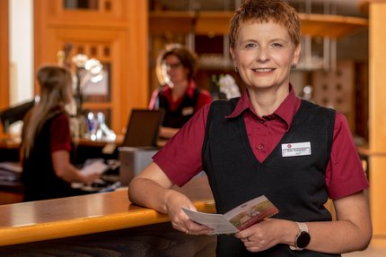 Eine Frau steht an der Rezeption, Geschäftsführung des Weinberghotel Edelacker GmbH