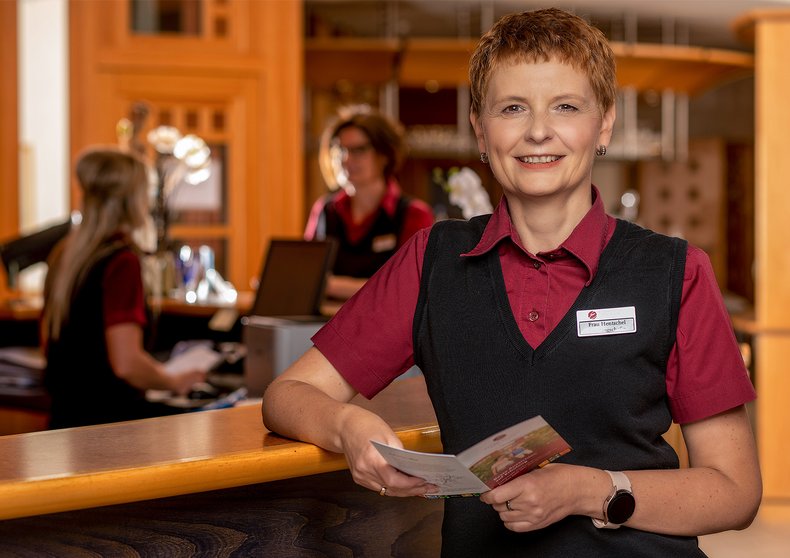 Eine Frau steht an der Rezeption, Geschäftsführung des Weinberghotel Edelacker GmbH