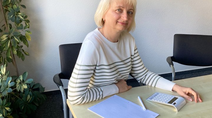 Eine Frau sitzt an einem Schreibtisch und blickt in die Kamera