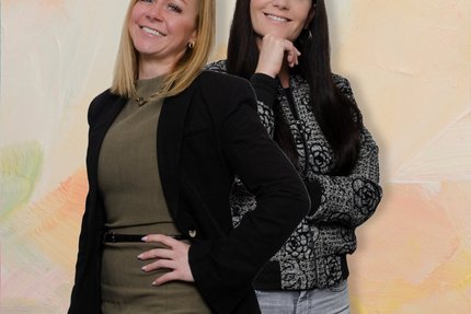 Zwei Frauen posen vor einer erdfarbenen Wand