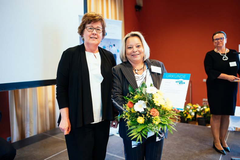 zwei Personen stehen auf einer Bühne, Ministerin überreicht das Landessiegel