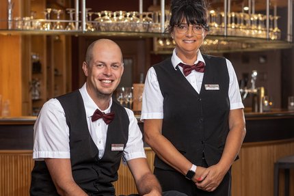 Ein MAnn und eine Frau stehen vor einem Thresen, Restaurant im Weinberghotel Edelacker GmbH