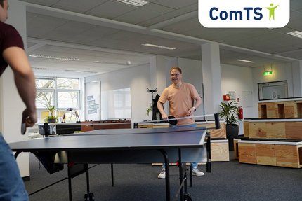 zwei junge Männer spielen Tischtennis in einem Büroraum