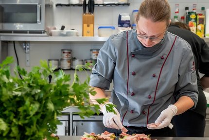 Ein Mann bereitet Essen zu, Küche im Weinberghotel Edelacker GmbH