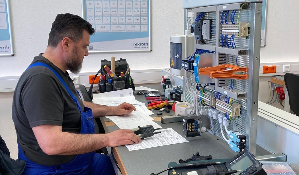 Ein Mann sitzt an einer Werkbank und überprüft elektrische Geräte