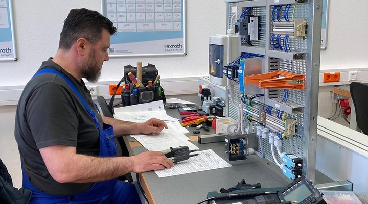 Ein Mann sitzt an einer Werkbank und überprüft elektrische Geräte