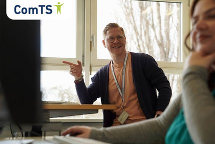 Ein junger Mann zeigt mit dem Finger auf einen Bildschirm