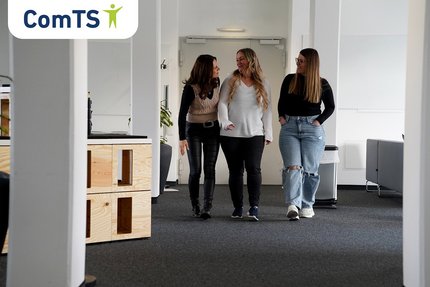 Drei Frauen laufen durch einen Büroraum