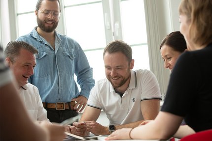 Das Team der hummelt und partner | Werbeagentur GmbH sitzen beratend an einem Tisch