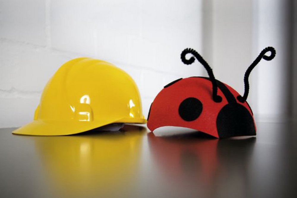 Ein Bauhelm und ein Kinderhut in Form eines Marienkäfers liegen nebeneinander