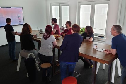 Ein Team der advanto Software GmbH bei einer Beratung vor einem großen Bildschirm