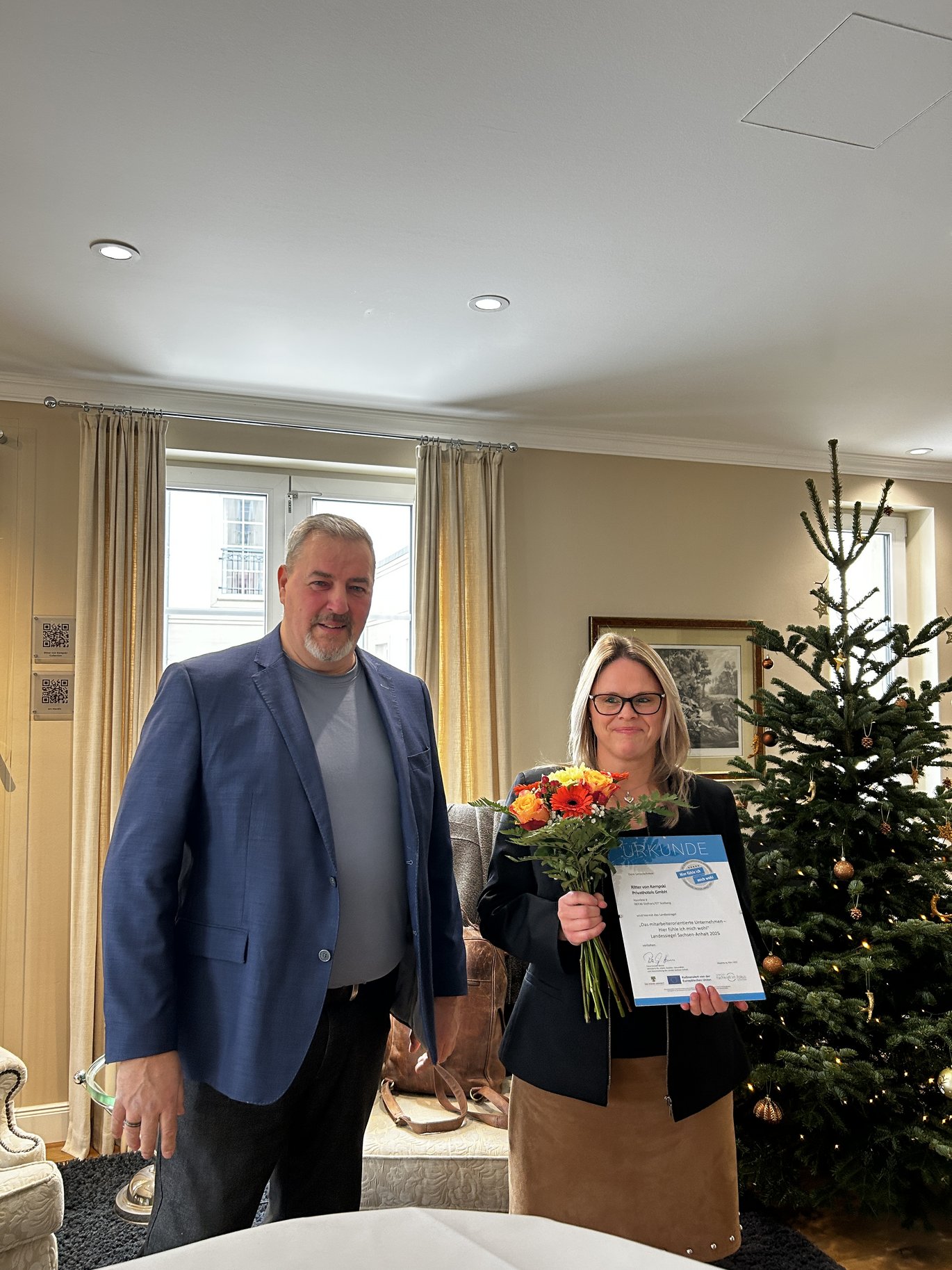 Eine Person übergibt einer weiteren Person die Urkunde zum Landessiegel