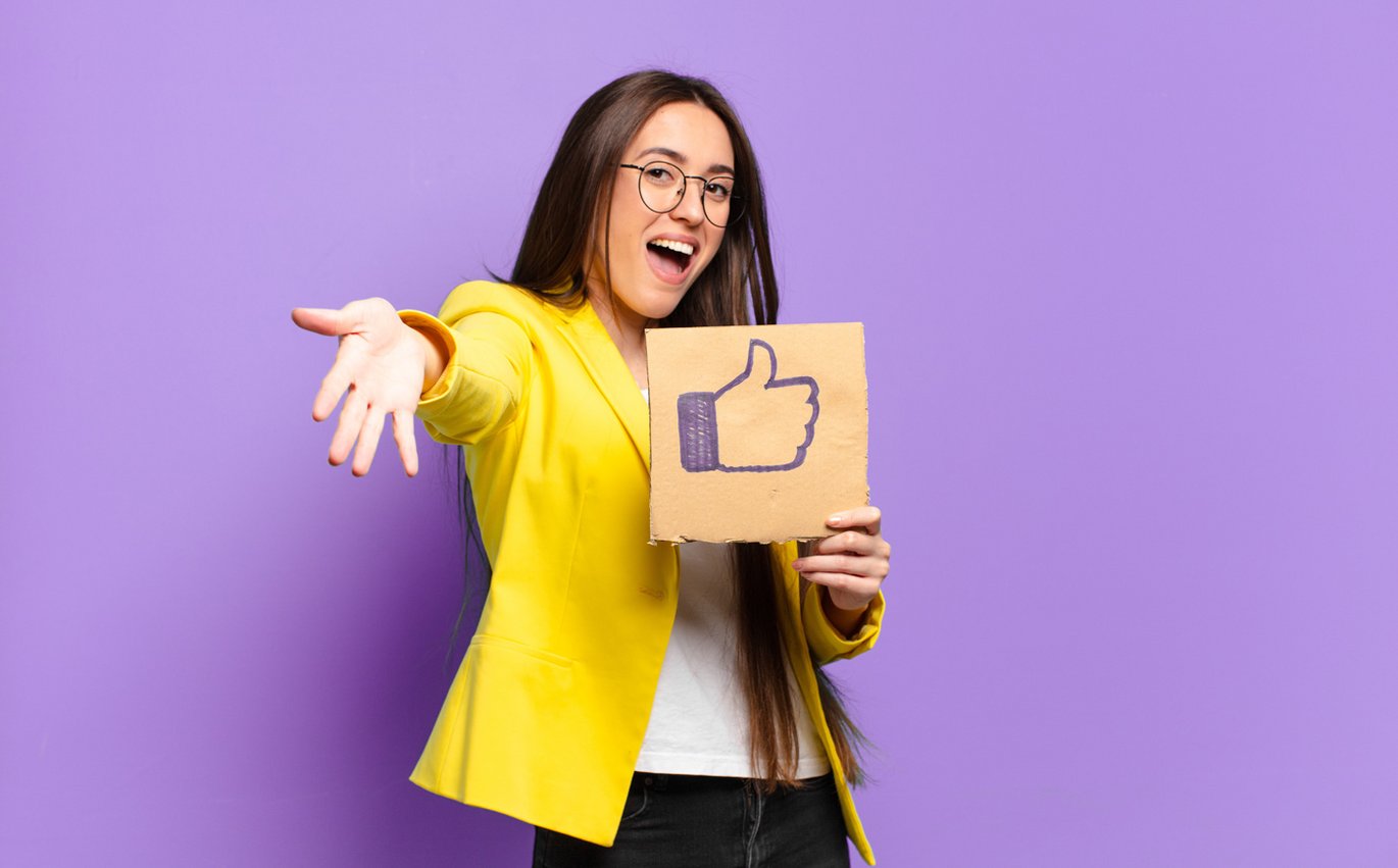 Eine junge Frau hält das Symbol "Gefällt mir" nach oben