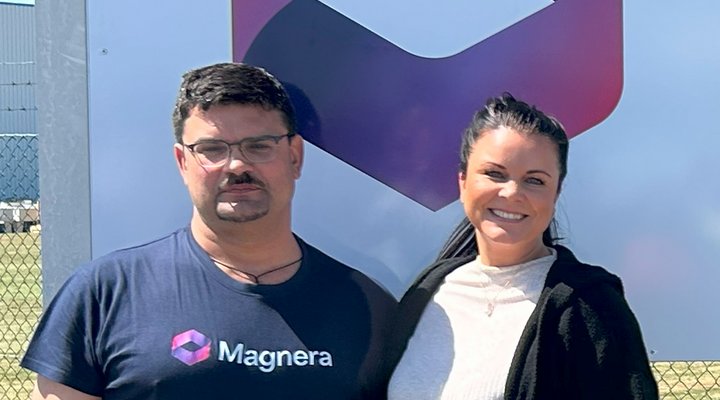 Ein Mann steht in Arbeitskleidung neben einer Frau vor einem Werbeschild